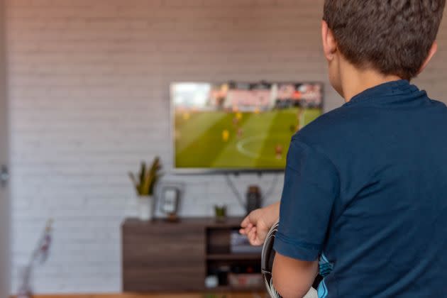Rear view of boy watching TV at home. Boy watching soccer or football game on tv. (Photo: Bojan Vlahovic via Getty Images)