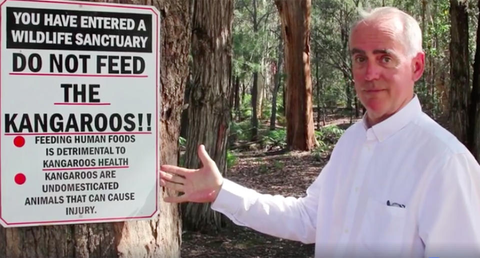 Lake Macquarie MP Greg Piper pictured with a sign informing people not to feed the kangaroos at Morisset Hospital. Source: Facebook/Kroosn Shuttle Services