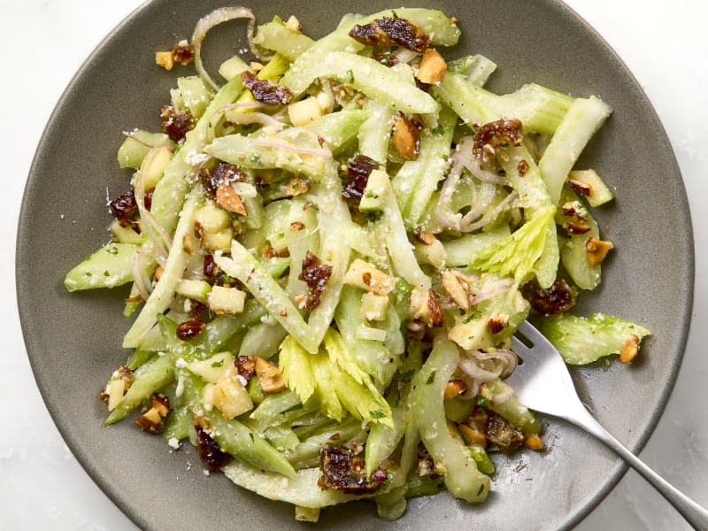 A gray plate with celery salad and a silver fork on a marble surface.