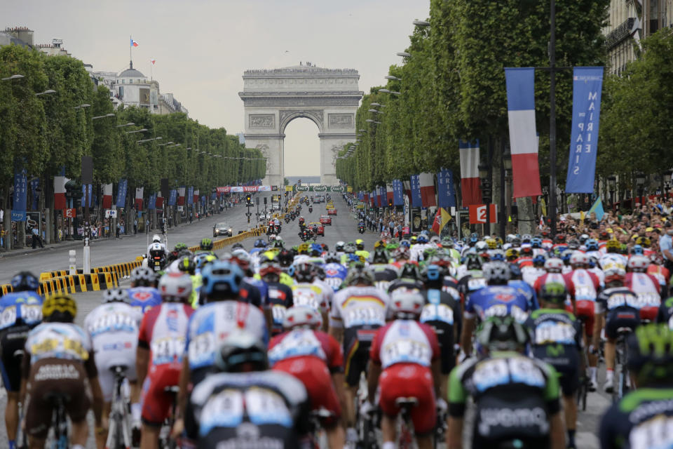 The pack rides on Champs Elysees towards the Arc de Triomphe during the twenty-first and last stage of the Tour de France cycling race over 137.5 kilometers (85.4 miles) with start in Evry and finish in Paris, France, Sunday, July 27, 2014. (AP Photo/Laurent Cipriani)