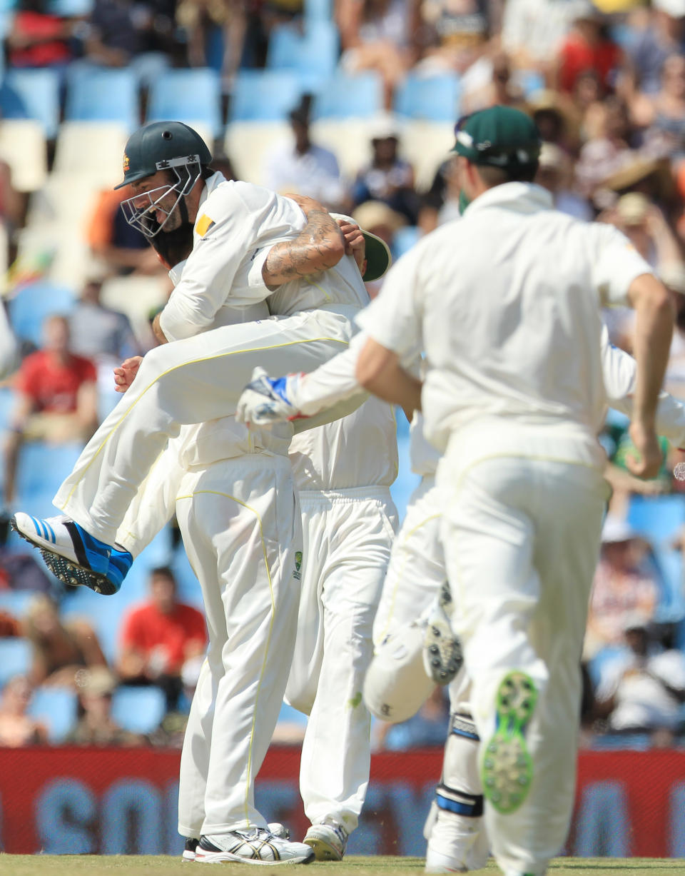 Australia's fielder Alex Doolan, center, jumps onto bowler Mitchell Johnson, left, after taking a catch on the fourth day of their cricket test match against South Africa at Centurion Park in Pretoria, South Africa, Saturday, Feb. 15, 2014. (AP Photo/ Themba Hadebe)