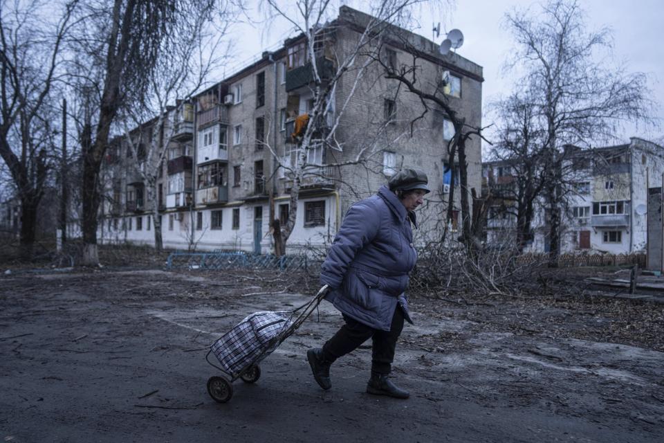 FILE - A local woman walks to the distribution point of humanitarian aid in front of housing which was damaged by Russian shelling in Kupiansk, Kharkiv region, Ukraine, on Dec. 28, 2022. Sweden holds the powerful presidency of the European Union for the next six months, but there are concerns in the 27-nation bloc that the strong influence of the hard-line far right at home will hold them back. (AP Photo/Evgeniy Maloletka, File)