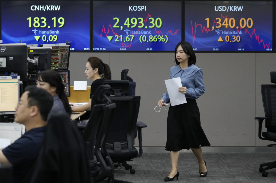 A currency trader passes by the screens showing the Korea Composite Stock Price Index (KOSPI), center, and the foreign exchange rate between U.S. dollar and South Korean won, right, at the foreign exchange dealing room of the KEB Hana Bank headquarters in Seoul, South Korea, Friday, Sept. 22, 2023. Asian shares were mixed on Friday after another slump on Wall Street driven by expectations that U.S. interest rates will stay high well into next year. (AP Photo/Ahn Young-joon)