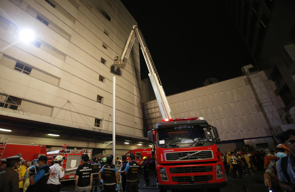Emergency rescue teams gather outside of the Central World mall complex, Wednesday, April 10, 2019, in downtown Bangkok, Thailand. A fire has broken out at a major mall complex in Thailand's capital, with initial reports from Thai emergency services are saying the fire has caused fatalities. (AP Photo/Sakchai Lalit)