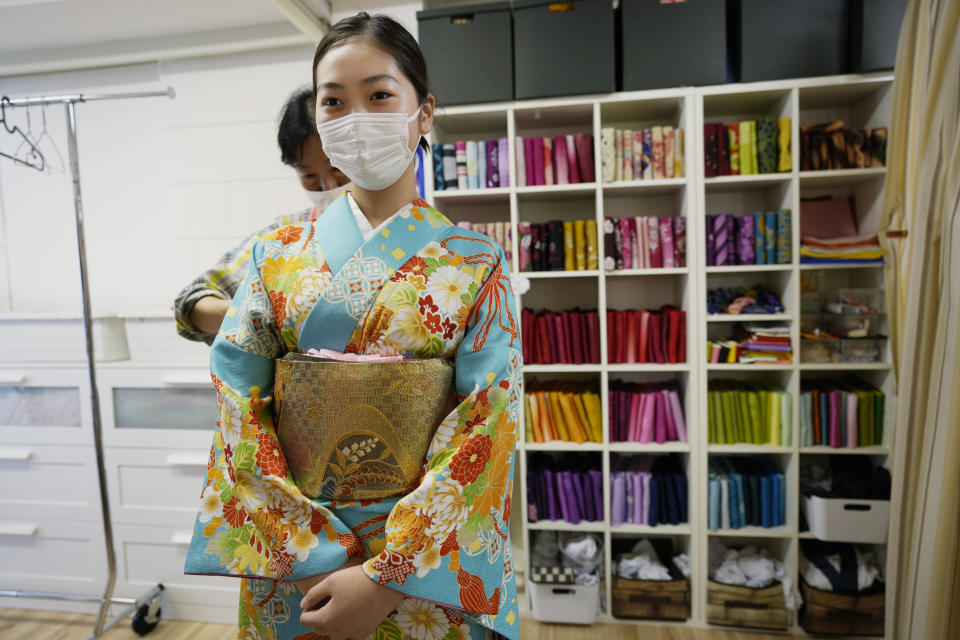 A Japanese woman gets help to wear kimono at Daikichi kimono rental shop Wednesday, June 22, 2022, in Tokyo's Asakusa area famous for sightseeing, before attending her family friend's wedding. Japan is bracing for a return of tourists from abroad, as border controls to curb the spread of coronavirus infections are gradually loosened. Yusuke Otomo, who owns the kimono rental shop, can barely contain his excitement. (AP Photo/Hiro Komae)