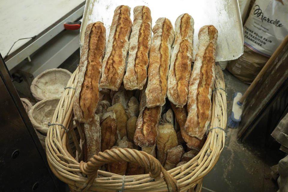 Baguettes are removed from the oven to a basket at Feru bakery in Louveciennes, west of Paris, Tuesday, Oct. 26, 2021. A worldwide increase in wheat prices after bad harvests in Russia is forcing French bakers to raise the price of that staple of life in France the baguette. Boulangeries around France have begun putting up signs warning their customers of an increase in the price of their favorite bread due to rising costs. (AP Photo/Michel Euler
