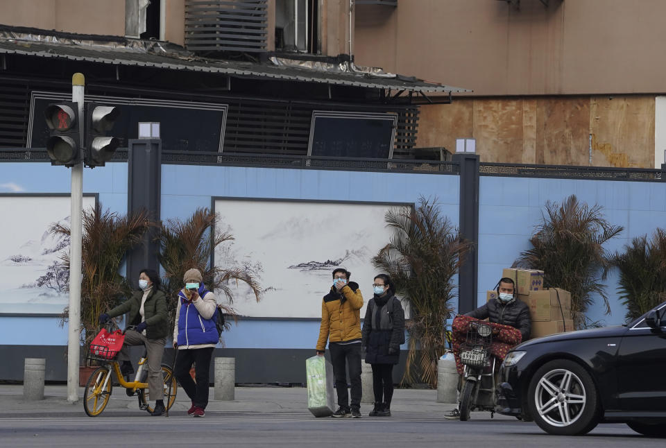 Residents wearing masks to protect from the coronavirus pass by the shutdown Huanan Seafood Market in Wuhan in central China's Hubei province on Friday, Jan. 15, 2021. Scientists initially suspected the coronavirus came from wild animals sold in the market. The market has since been largely ruled out but for the visiting WHO team of international researchers it could still provide hints to how the virus spread so widely. (AP Photo/Ng Han Guan)