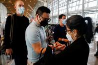 Airport staff puts a wristband on a traveller upon his arrival at the Kuala Lumpur International Airport under the Malaysia-Singapore Vaccinated Travel Lane programme, in Sepang