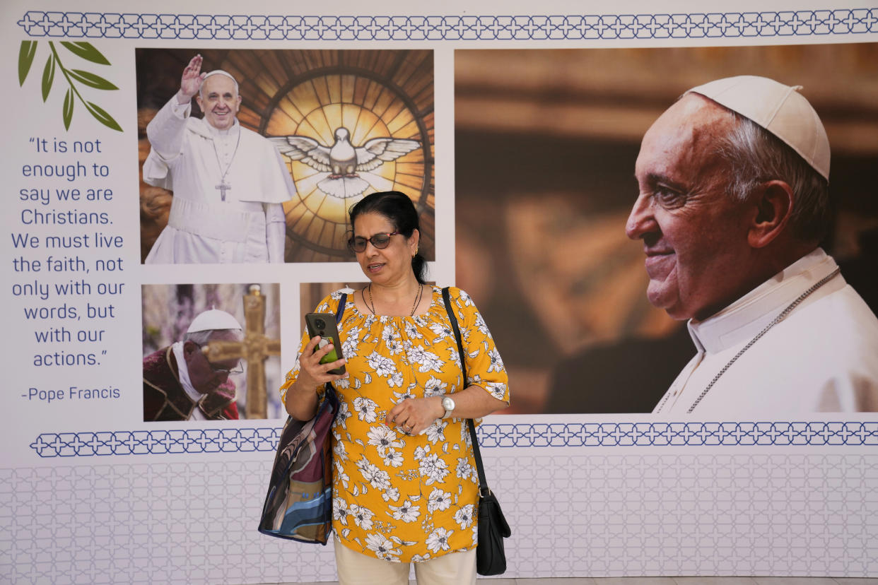 A woman speaks on her mobile phone as she stands in front of posters that shows the Pope Francis, at Sacred Heart church in Manama, Bahrain, Wednesday, Nov. 2, 2022. Pope Francis is making the Nov. 3-6 visit to participate in a government-sponsored conference on East-West dialogue and to minister to Bahrain's tiny Catholic community, part of his effort to pursue dialogue with the Muslim world. (AP Photo/Hussein Malla)