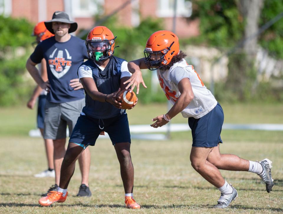 Quarterback Ammiel Steele hands off during football practice at Escambia High School on Monday, April 25, 2022.