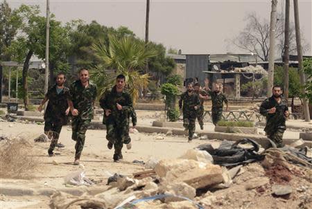 Forces loyal to Syria's President Bashar al-Assad run through Aleppo's Bustan al-Qasr crossing after their release by rebels May 7, 2014. REUTERS/George Ourfalian