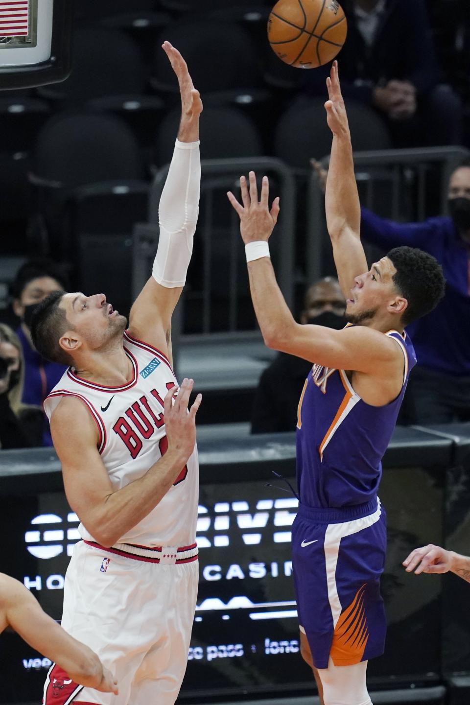 Phoenix Suns guard Devin Booker, right, shoots over Chicago Bulls center Nikola Vucevic during the second half of an NBA basketball game Wednesday, March 31, 2021, in Phoenix. (AP Photo/Ross D. Franklin)