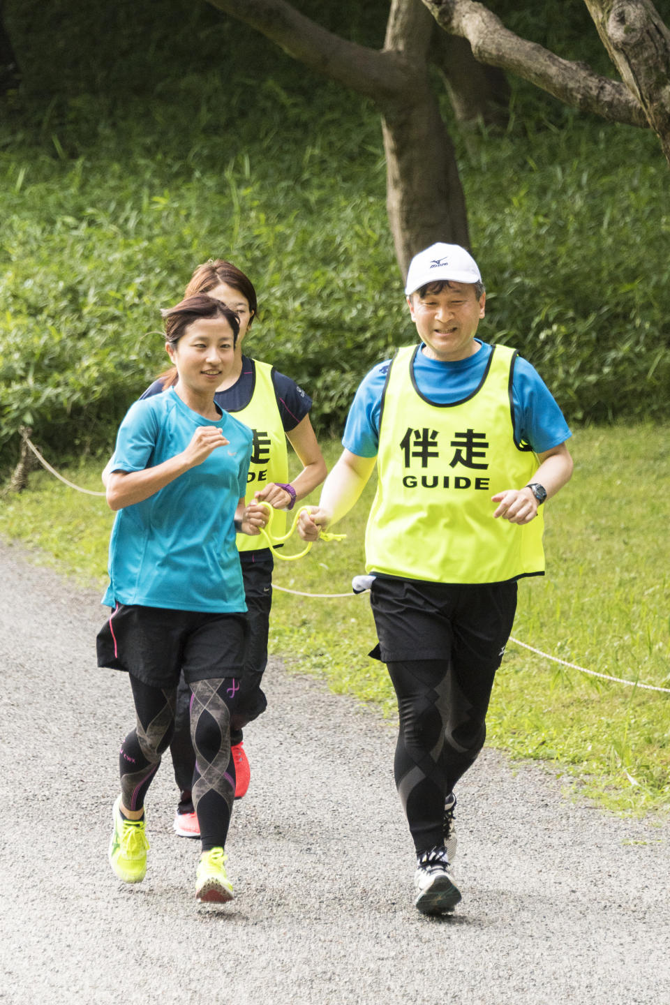 In this June 26, 2018, photo provided by the Imperial Household Agency of Japan, Japan's Crown Price Naruhito, right, guides Rio Paralympics women's T12 marathon silver medalist Misato Michishita, left, as they run together at Akasaka Imperial Garden in Tokyo. Naruhito celebrates his 59th birthday on Saturday, Feb. 23, 2019. (Imperial Household Agency of Japan via AP)