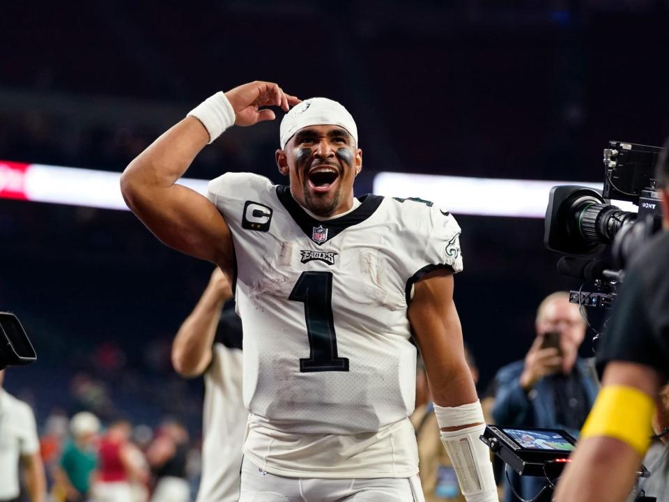 Jalen Hurts raises his hand and yells in celebration while walking off the field after an Eagles game.