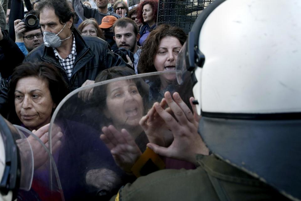 Protesting civil servants confront riot police outside the private office of Greek Public Administration Reform Minister Kyriakos Mitsotakis in central Athens, on Thursday, March 20, 2014. Scores of striking schoolteachers and other civil servants occupied Mitsotakis' office Thursday to protest planned public sector layoffs, under cost-cutting reforms demanded by the debt-mired country's bailout creditors. (AP Photo/Petros Giannakouris)