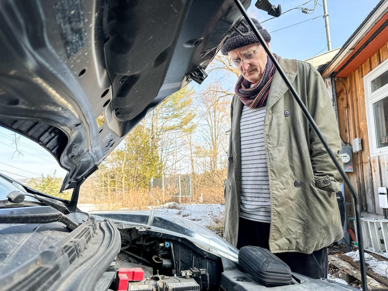 Musician Brian Sanderson examines his Nissan Leaf, which was left in his driveway last week after breaking down a fifth time. (Stu Mills/CBC - image credit)