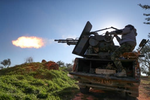 A Turkey-backed Syrian fighter fires a truck-mounted gun in Idlib province in northwestern Syria