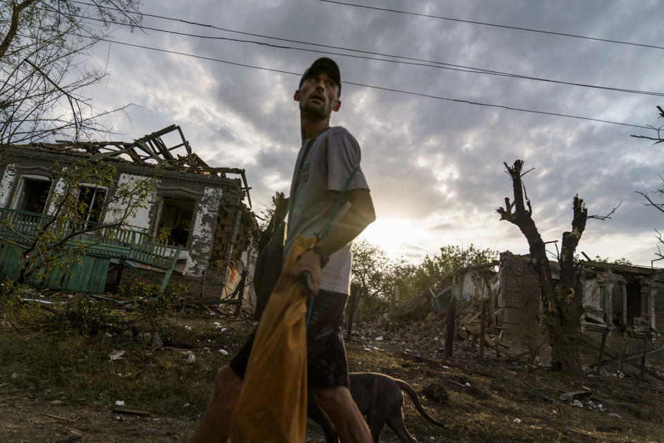 Un hombre camina con un perro frente a casas dañadas por un ataque con cohetes horas antes el 16 de agosto de 2022 en Kramatorsk, en el este de Ucrania, mientras los bombardeos rusos continuaban golpeando pueblos y aldeas en la provincia de Donetsk. (AP Foto/David Goldman)