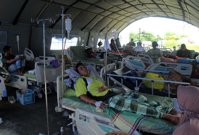 Injured people are treated at temporary shelter outside hospital following earthquake in Mamuju