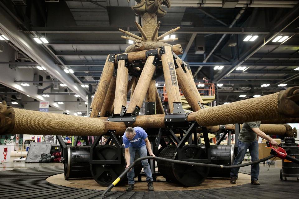 Hubie Cushman, center, a contractor with Rogue's events division, cleans up the Wheel of Pain with co-worker Robert Valentine, left, after they finished assembling the Strongman event for the Arnold Sports Festival in 2019.