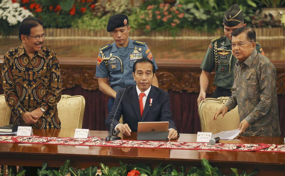 Indonesia President Joko Widodo, center, takes his seat as his deputy Jusuf Kalla, right, and Agrarian and Spatial Planning Minister Sofyan Djalil, left, looks on before a press conference, at the palace in Jakarta, Indonesia, Monday, Aug. 26, 2019. Indonesia's president has announced to relocate the country's capital from overcrowded, sinking and polluted Jakarta to East Kalimantan province. (AP Photo/Achmad Ibrahim)