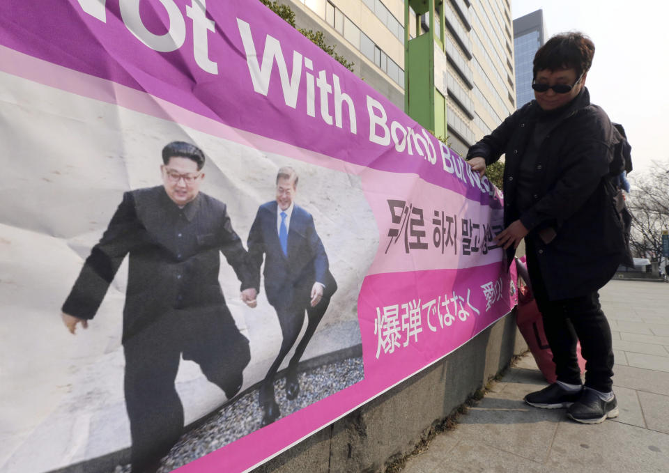 A woman displays a banner showing a photo of North Korean leader Kim Jong Un and South Korean President Moon Jae-in, right, to wish for peace on the Korean Peninsula, in Seoul, South Korea, Tuesday, March 19, 2019. International journalists' organizations have expressed concern over South Korea's press freedoms after the country's ruling party singled out a Bloomberg reporter over what it claimed was a "borderline treacherous" article insulting Moon, resulting in threats to the reporter's safety. (AP Photo/Ahn Young-joon)