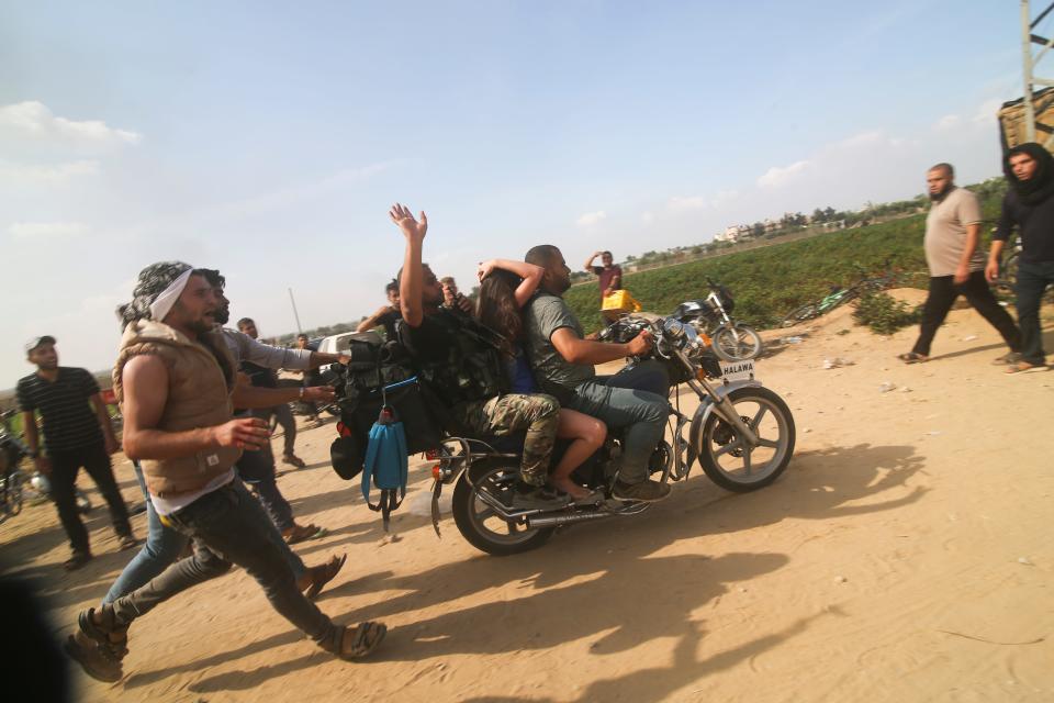 Palestinians transport a captured Israeli civilian, center, from Kfar Azza kibbutz into the Gaza Strip on Saturday, Oct. 7, 2023. The militant Hamas rulers of the Gaza Strip carried out an unprecedented, multi-front attack on Israel at daybreak Saturday, firing thousands of rockets as dozens of Hamas fighters infiltrated the heavily fortified border in several locations by air, land, and sea and catching the country off-guard on a major holiday. (AP Photo/Hatem Ali)