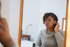 Black woman looking at herself in the mirror