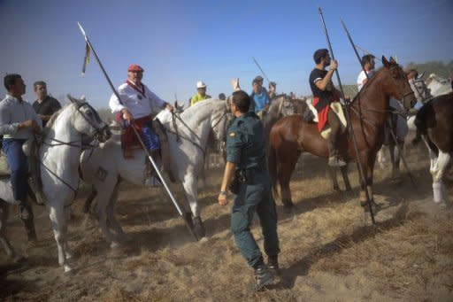 A Spanish civil guard gives instructions to men riding horses during the "Toro de la Vega" festival in Tordesillas. At least one horseman speared the bull in a fatal strike by the bridge, an AFP photographer saw, but the lancing took place outside the official area, so the tournament was declared null