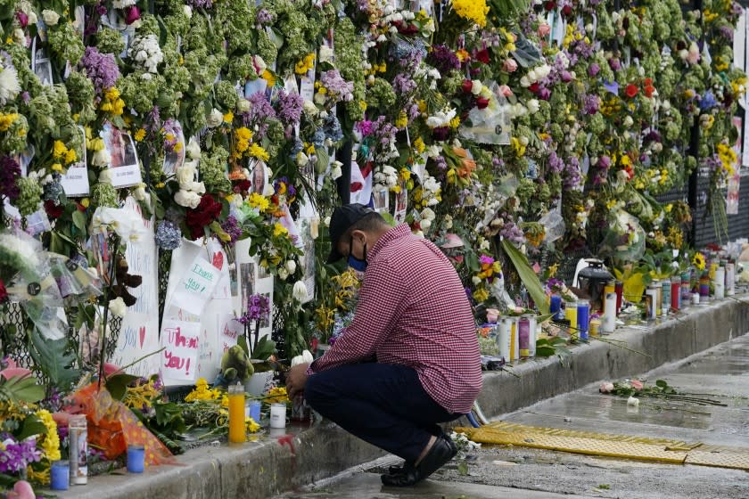 Local resident Louis Thompson, who is missing friends in the collapse of Champlain Towers South, kneels in front of a makeshift memorial to the scores of people who remain missing or were killed, nearly a week after the condo building partially collapsed, Wednesday, June 30, 2021, in Surfside, Fla.. (AP Photo/Gerald Herbert)