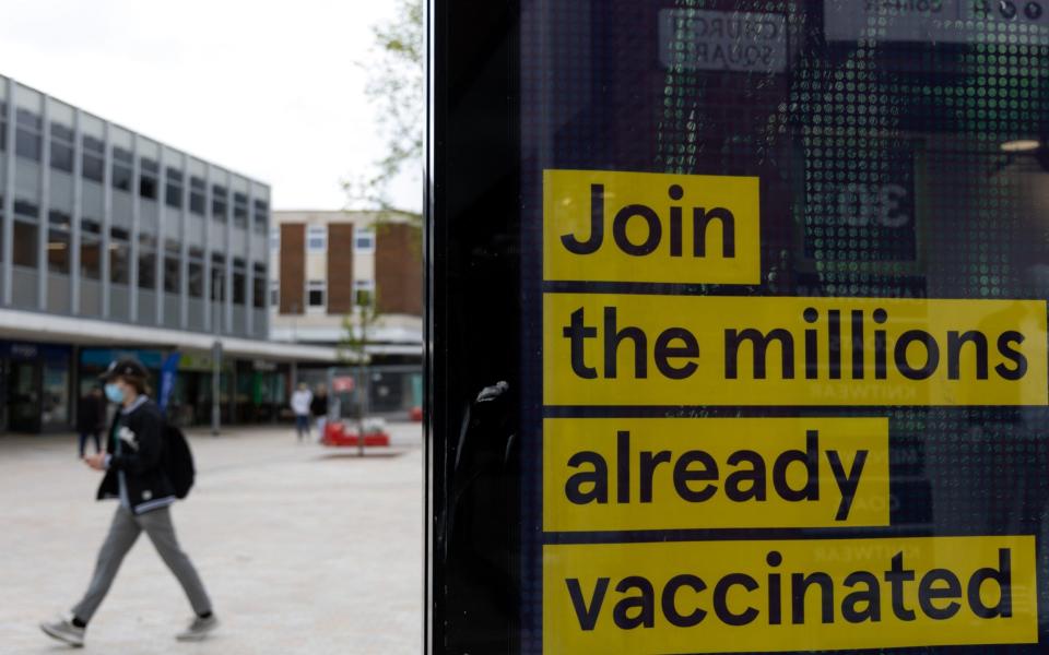 A pedestrian passes a sign advertising Covid-19 vaccinations in Bedford - Jason Alden/Bloomberg