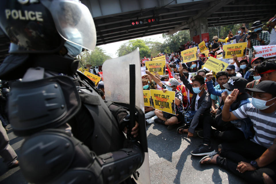 Anti-coup protesters flash the three-fingered salute in front of riot police as they sit on the road outside the Hledan Centre in Yangon, Myanmar Friday, Feb. 19, 2021. The daily protests campaigning for civil disobedience in Myanmar are increasingly focusing on businesses and government institutions that sustain the economy. (AP Photo)