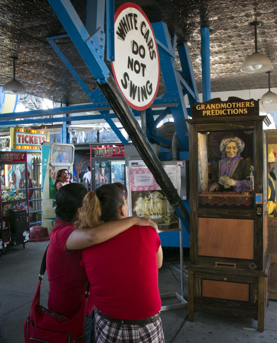 This June 12, 2013 photo shows a couple looking at the 90-year-old fortune telling machine "Grandma's Predictions," which was restored after damage in superstorm Sandy at the amusement park in the Coney Island neighborhood in the Brooklyn borough of New York. (AP Photo/Bebeto Matthews)