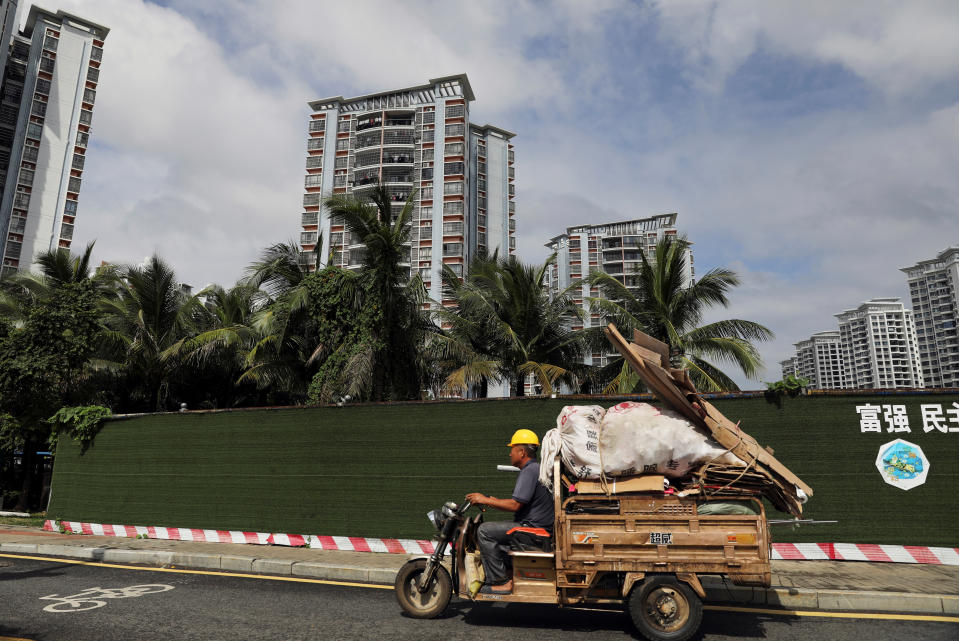 A man drives a tricycle past residential buildings in Sanya, Hainan province, China November 26, 2020. Picture taken November 26, 2020. REUTERS/Tingshu Wang