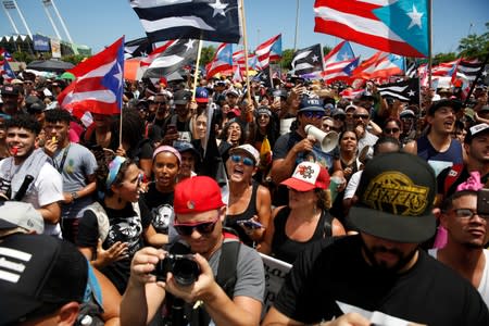 People chant slogans as they wave Puerto Rican flags during a protest calling for the resignation of Governor Ricardo Rossello in San Juan