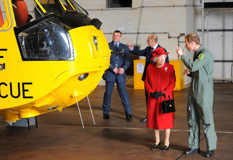 Britain's Queen Elizabeth II (2nd R) is shown a Sea King helicopter by her grandson Prince William (R) during a visit to RAF Valley in Anglesey, Wales on April 1, 2011. Britain's Queen Elizabeth II and Prince Philip, The Duke of Edinburgh today visited RAF Valley in Anglesey and were given a personal tour of an RAF search and rescue helicopter by Prince Willam. AFP PHOTO/ANDREW YATES (Photo credit should read ANDREW YATES/AFP via Getty Images)