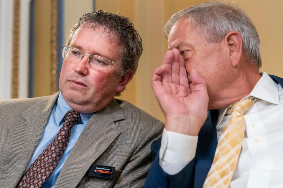 Rep. Thomas Massie, R-Ky., left, wearing a pin simulating the increasing federal debt, listens to Rep. Ralph Norman, R-S.C., as the House Rules Committee meets Tuesday, May 30, 2023, to prepare the debt limit bill for a vote on the floor.