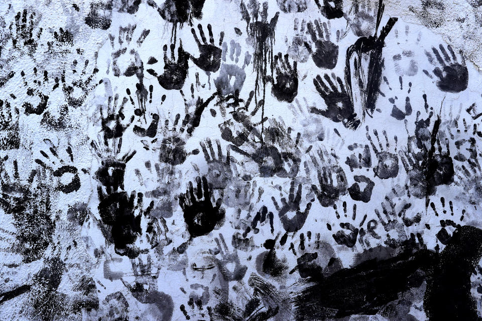In this photo taken on Friday, Sept. 6, 2019, hand prints are made by people painted with black grease on a wall during the traditional festivities of the Cascamorras festival in Baza, Spain. During the Cascamorras Festival, and according to an ancient tradition, participants throw black paint over each other for several hours every September 6 in the small town of Baza, in the southern province of Granada. The "Cascamorras" represents a thief who attempted to steal a religious image from a local church. People try to stop him, chasing him and throwing black paint as they run through the streets. (AP Photo/Manu Fernandez)