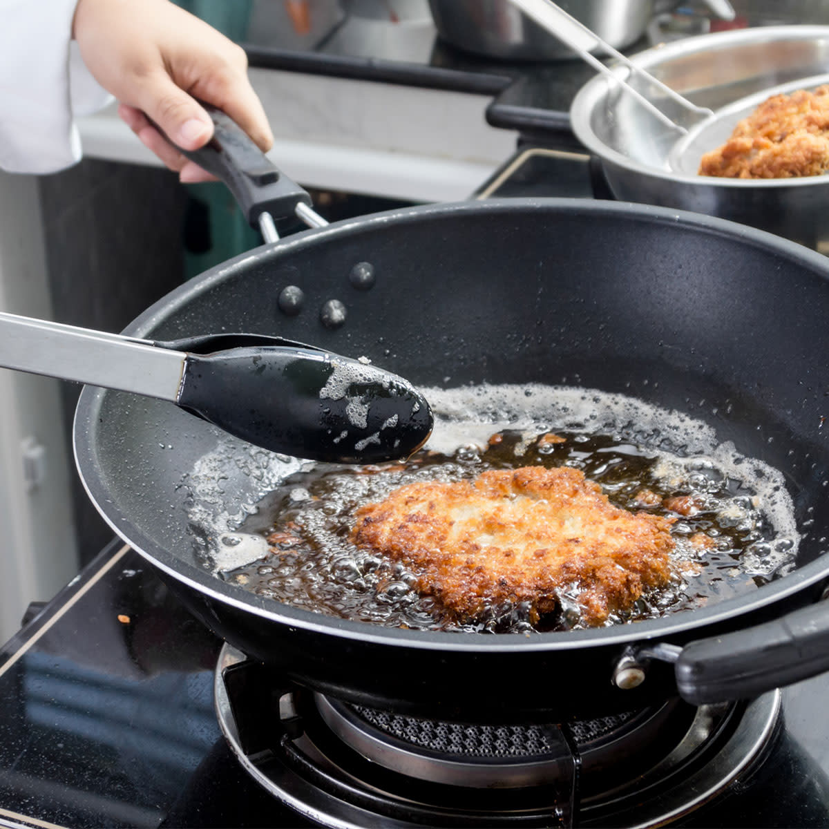 Woman frying cutlets at home