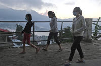Naga girls wearing face masks as a precautionary measure against the coronavirus walk at dusk in Kohima, capital of the northeastern Indian state of Nagaland, Thursday, Oct. 29, 2020. India's confirmed coronavirus caseload surpassed 8 million on Thursday with daily infections dipping to the lowest level this week, as concerns grew over a major Hindu festival season and winter setting in. (AP Photo/Yirmiyan Arthur)