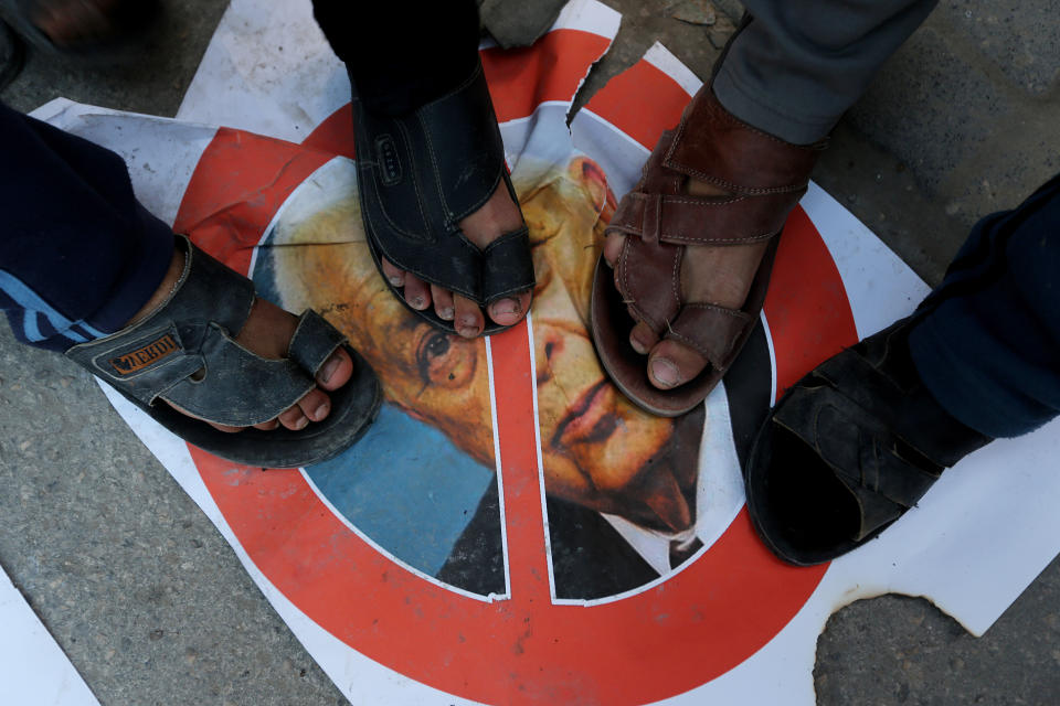 Palestinians stand over a picture of the former Israeli Prime Minister Ariel Sharon in Khan Younis, southern Gaza Strip, Saturday, Jan. 11, 2014. Sharon was loathed by many Palestinians as a bitter enemy who did his utmost to sabotage their independence hopes — by leading military offensives against them in Lebanon, the West Bank and Gaza and a settlement drive on the lands they want for a state. Sharon died Saturday, eight years after a debilitating stroke put him into a coma. He was 85. (AP Photo/Hatem Moussa)