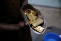 An employee holds gold bars before the refining process at AGR (African Gold Refinery) in Entebbe