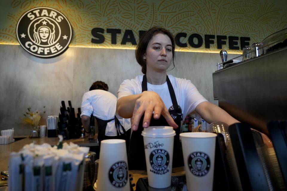 A worker at a Stars Coffee in Moscow makes drinks for customers. A cup features handwritten text.