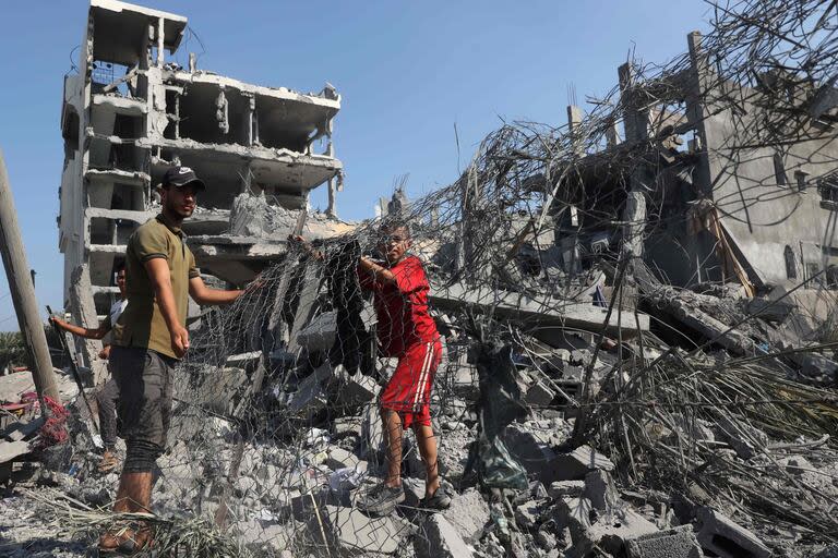 Los palestinos frente a la destrucción de un edificio en Deir el-Balah, en el centro de la Franja de Gaza, el 7 de agosto de 2024, tras el bombardeo israelí en medio del conflicto en curso entre Israel y el grupo militante palestino Hamas
