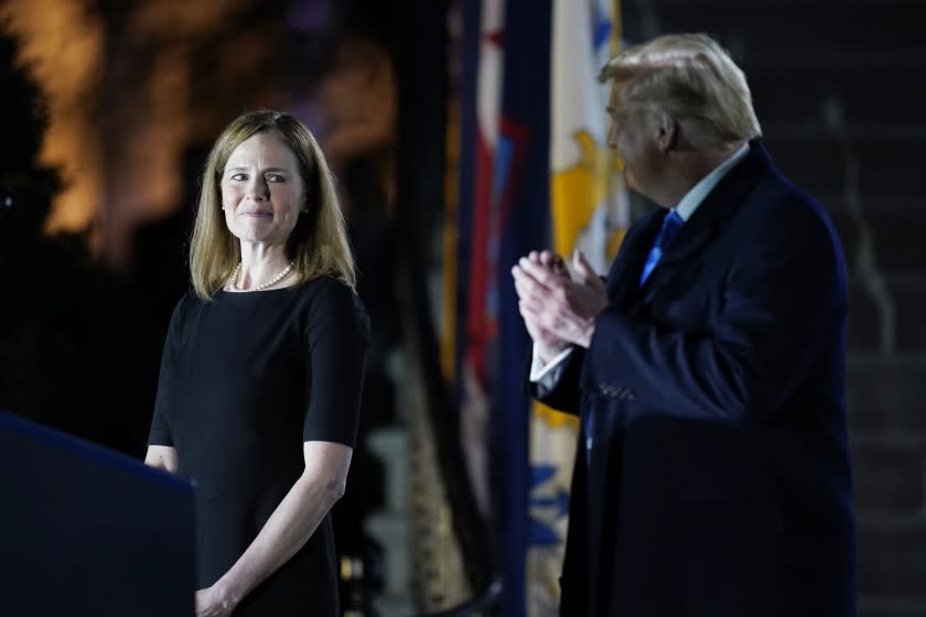 President Donald Trump looks toward Amy Coney Barrett, before Supreme Court Justice Clarence Thomas administers the Constitutional Oath to her on the South Lawn of the White House in Washington, Monday, Oct. 26, 2020, after Barrett was confirmed by the Senate earlier in the evening. (AP Photo/Patrick Semansky)