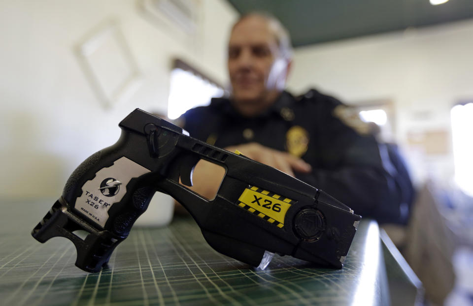 ADDS AN UPDATE FROM THE FRENCH GOVERNMENT - FILE - In this Nov. 14, 2013, file photo, a Taser X26 sits on a table in Knightstown, Ind. After France banned police chokeholds, the government responded to growing officer discontent by announcing it would test stun guns for wider use, adding to the ranks of European law enforcement agencies that have recently adopted the weapons that many in the U.S. equate with excess police violence. The French government later backed away from a complete chokehold ban. (AP Photo/Michael Conroy, File)