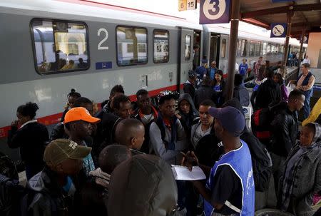 A volunteer talks to a group of migrants as police officers stand in front of the door of a train bound for Munich, Germany, at Bolzano railway station, Italy May 28, 2015. REUTERS/Stefano Rellandini