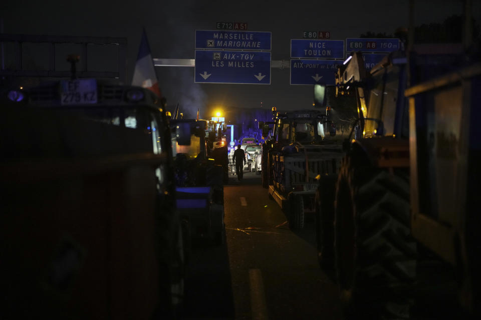 Farmers spend the night at a highway barricade in Aix-en-Provence, southern France, Tuesday, Jan. 30, 2024. France's protesting farmers encircled Paris with traffic-snarling barricades Monday, using hundreds of lumbering tractors and mounds of hay bales to block highways leading to France's capital to pressure the government over the future of their industry. (AP Photo/Daniel Cole)