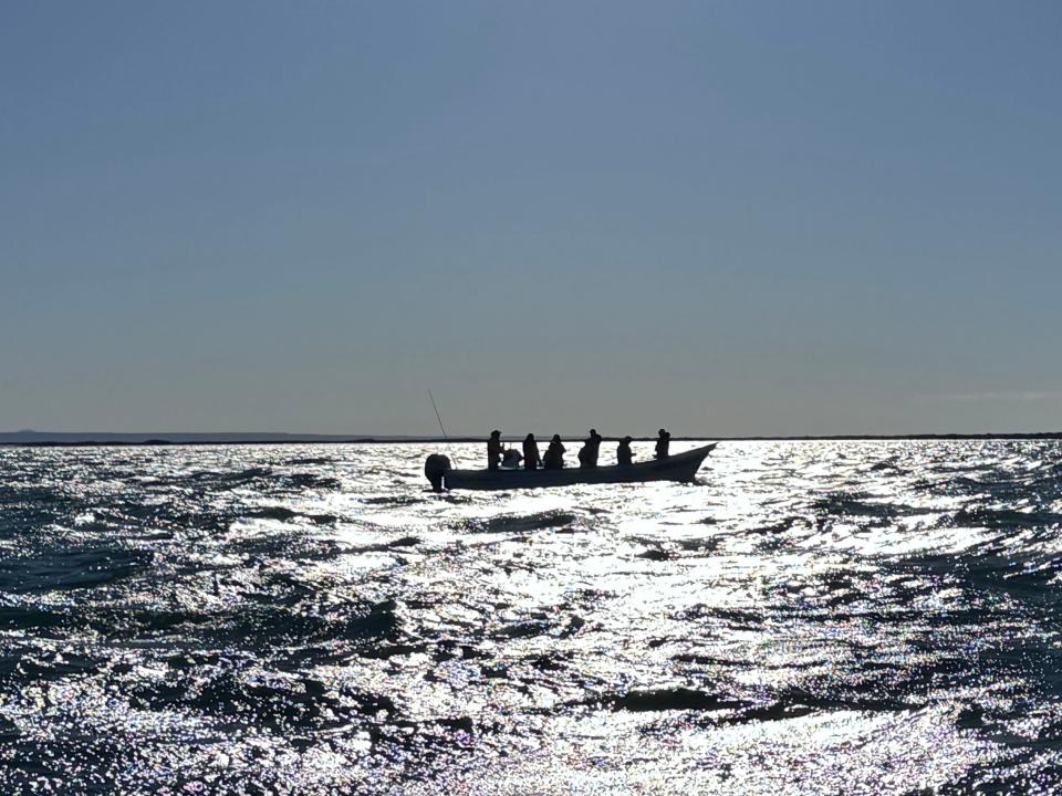 The shadow of people on a small boat in the ocean.