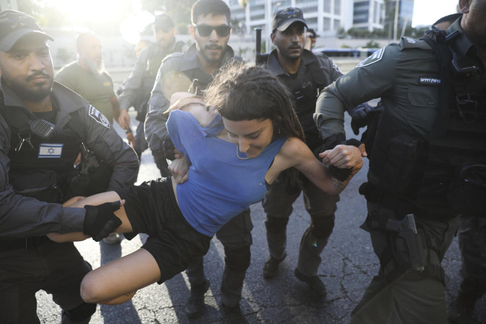 FILE - In this Wednesday, July 3, 2019 file photo, police detain a woman during a protest in Tel Aviv, Israel during another day of violent protests after community activists called for renewed street demonstrations in response to the killing of Ethiopian-Israeli teenager Solomon Teka by an off-duty police officer. On Friday, July 19, 2019, The Associated Press reported on stories circulating online incorrectly asserting that a video, which was made a day earlier, shows migrants in Calais, France, their faces covered to conceal their identities, taking rocks from barriers on a highway and hurling them onto a roadway to disrupt traffic. The misidentified video was shot in early July during unrest in Israel, following the killing of the teenager. (AP Photo/Oded Balilty)